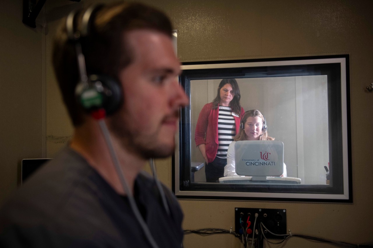 Researchers in a sound booth analyze a patient's hearing.